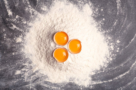 Dough, baking and cooking background. Flour and eggs on a dark wooden kitchen background as...