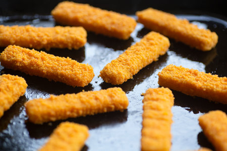 Fish sticks background. Fried fish sticks on a culinary baking sheet as an appetizer and food for...