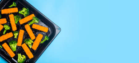 Fish sticks banner background. Fried fish sticks and baked broccoli on a cooking tray as an appetizer and food for children and parties. Copy spaceの写真素材