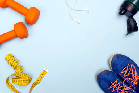 Sport concept with sport equipment composition. Sneakers, dumbbells, bottle of water on bright blue backgroundの写真素材