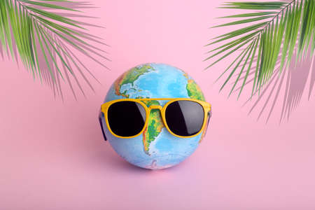 Travel summer concept. Globe in sunglasses on a colored background. Sun, vacation and tourism creative idea.の写真素材