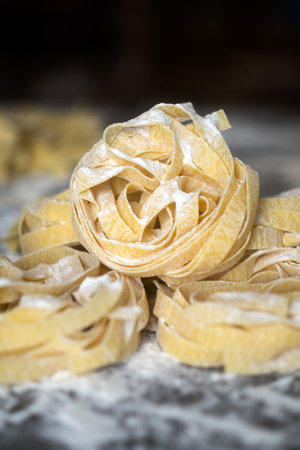 Homemade uncooked pasta on black background. Making fresh italian fettuccine.の写真素材