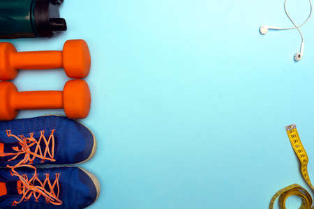 Sport concept with sport equipment composition. Sneakers, dumbbells, bottle of water on bright blue backgroundの写真素材