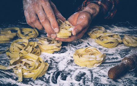 Homemade uncooked pasta on black background. Making fresh italian fettuccine.の写真素材