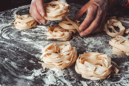 Homemade uncooked pasta on black background. Making fresh italian fettuccine.の写真素材
