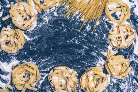 Homemade uncooked pasta on black background. Making fresh italian fettuccine.の写真素材