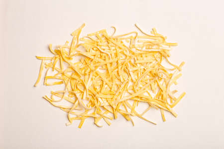 Fresh pasta background. Homemade Italian fettuccine pasta cooked in the home kitchen with fresh eggs and flour on a white light background. Italian food and cuisine conceptの写真素材