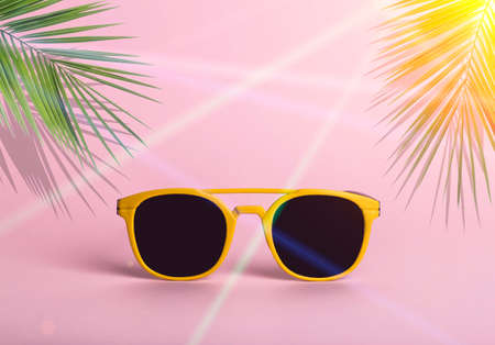 Summer and sunglasses concept. Bright beach sunglasses on a pink background with tropical palm leaves. Vacation, beach, tropics, vacation, tourism creative idea.の写真素材