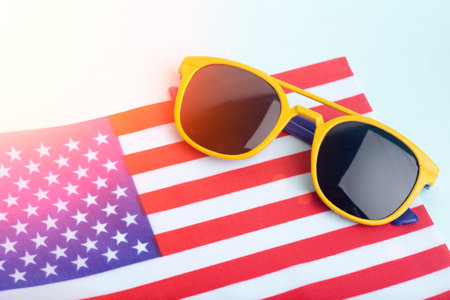 Summer sunglasses on the USA flag and colored background. Vacation, summer, sun and USA vacation concept. High quality photoの写真素材