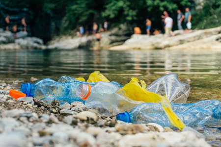 PLASTIC POLLUTION in the river. Dirty plastic bottles and bags on a garbage. River pollution, plastic in water. Pollution and recycle eco concept.の写真素材