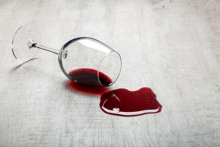 Wooden floor with overturned glass of red wine. Spilled wine on a wooden laminate parquet floor with moisture protection.の写真素材