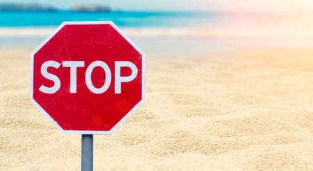 Lockdown concept. Stop sign on the beach by the sea. Ban on the sea, beaches, recreation and vacations. Coronavirus restrictions and bansの写真素材