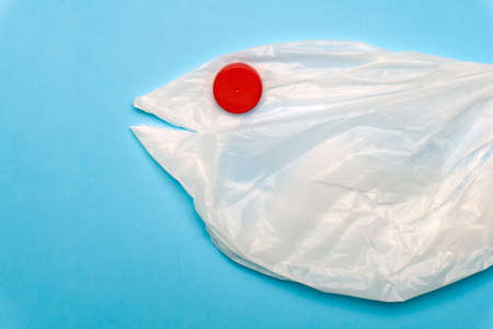 A plastic bag in the shape of a sea fish on a blue background. Plastic pollution ocean and sea concept. Creative, minimal conceptの写真素材