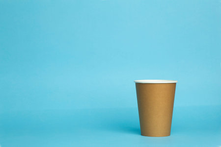 Paper cup for a drink on a blue background. Minimal concept.