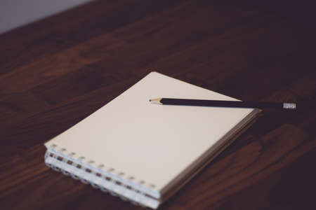 Notepad with pencil on a wooden table. White notebook (sketchbook) for sketches or notes.の写真素材