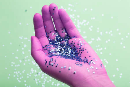 Woman's hand is holding pink glitter. Celebration, party, birthday magic background.の写真素材