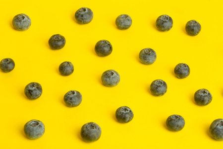 Blueberry berries on a yellow background. A scattering of berries on a colored yellow background....