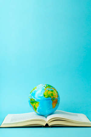 Education and globalism concept. Globe on an open book on a table in a university class on a blue backgroundの写真素材