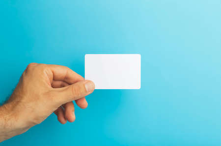 Empty plastic card in hand on colored background. ID or credit money card isolateの写真素材