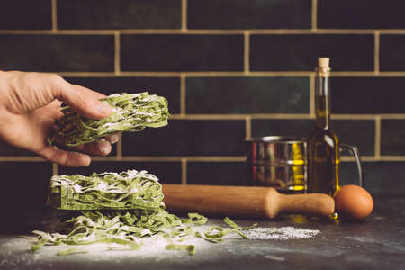 Italian pasta food background. Vegan italian pasta fresh with spinach - Spinach Fettuccine Alfredo Pasta on a dark background. Old kitchen background. Copy spaceの写真素材