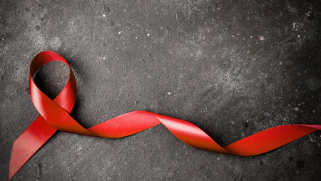 The red ribbon on a dark gray background. The symbol of The World AIDS Day or cancer or HIV...