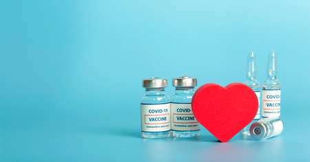 Vaccines against COVID-19. Glass medical vials with liquid. Ampoule with coronavirus vaccine and heart on a medical table..の写真素材