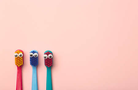 Kids toothbrushes of different colors on a pink background. Teeth and oral hygiene for childrenの写真素材