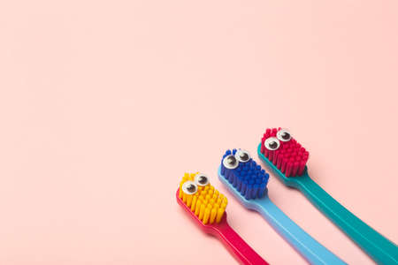 Kids toothbrushes of different colors on a pink background. Teeth and oral hygiene for childrenの写真素材