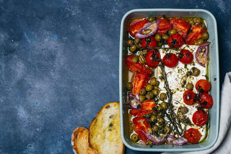 Baked vegetables with feta cheese, olives, onions, Provencal herbs, spices, olive oil and tomatoes. Home cooking concept.の写真素材
