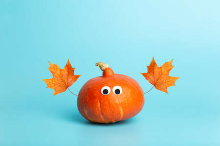 Pumpkin for halloween and thanksgiving on empty blue minimal background. Funny autumn pumpkin with eyes for children. Cheerful and funny vegetables concept.の写真素材