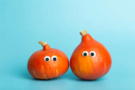 Pumpkin for halloween and thanksgiving on empty blue minimal background. Funny autumn pumpkin with eyes for children. Cheerful and funny vegetables concept.の写真素材