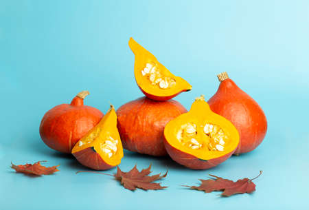 Pumpkin for halloween and thanksgiving on empty blue minimal background. Autumn harvest of yellow pumpkin with slices and leavesの写真素材