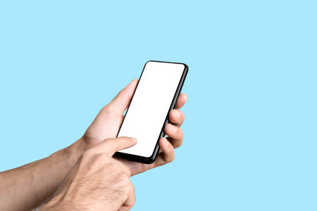 Empty smartphone in hand on colored blue banner background. Mockup phone with blank screen on...