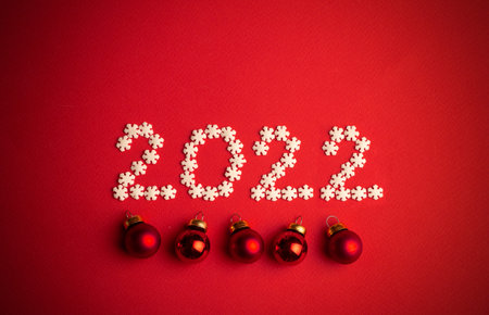 New Year 2022. Creative number written in white snowflakes on a red background for design. New Year...