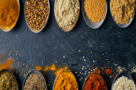 Spices in spoons background. Varieties of spices turmeric, pepper, chili, coriander, cinnamon and peppers for cooking. Culinary food concept.の写真素材