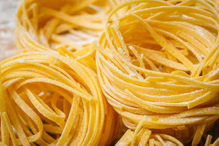 Fresh pasta food. Homemade Italian pasta cooked on a wooden background in a rustic style decorated with egg and flour.の写真素材