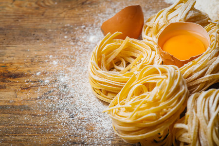Fresh pasta food. Homemade Italian pasta cooked on a wooden background in a rustic style decorated with egg and flour.の写真素材