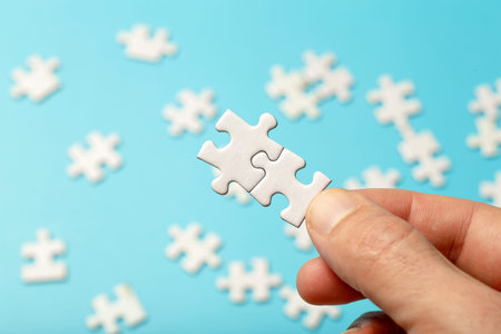 Puzzle pieces are connected. White puzzle pieces in hand on a blue background. Business, partner,...