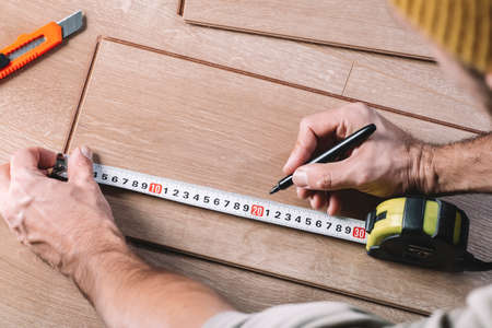 Installing laminate flooring in a room or office. Wooden parquet boards and tools. Construction and decorative works for the finishing of housingの写真素材