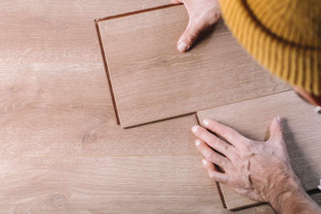 Installing laminate flooring in a room or office. Wooden parquet boards in the hands of a worker. Construction and decorative works for the finishing of housingの写真素材