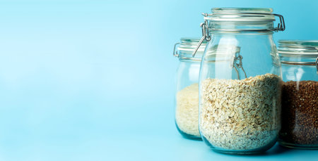 Cereals oatmeal, buckwheat, rice in glass jars in the kitchen. Gluten free concept. Varieties of cereals for making healthy homemade food and mealsの写真素材