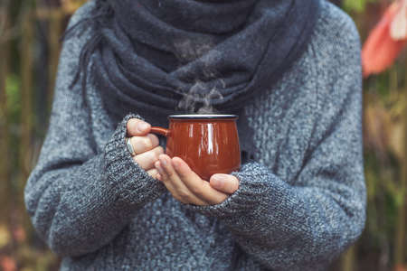 Cup of coffee or tea drink in female hands in the autumn park. Autumn fall mood, cozy, love and romance concept. Copy spaceの写真素材