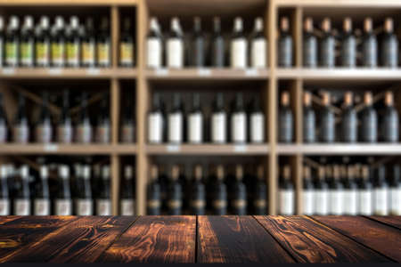 Wine wooden table background. Blurred wine shop with bottles on the counter.の写真素材