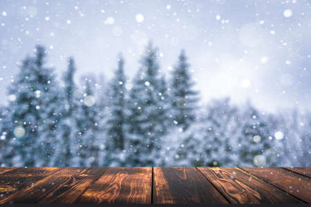 Winter forest with wooden table background. Blurred snow landscape and empty rustic table for product or merchandise.の写真素材
