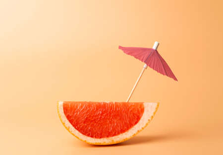 Grapefruit slice on a orange background. Summer, vacation and travel minimal concept.の写真素材