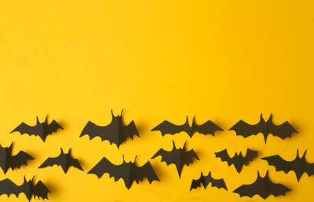 Halloween background. Black bats cut from paper on a yellow background. Halloween decor and decorations for the holiday, copy space.の写真素材