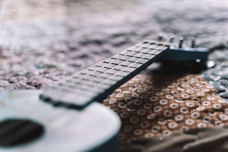 Ukulele guitar on the bed. Selected focus. Hawaiian national acoustic guitar for folk music and learning.の写真素材