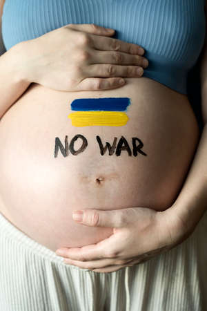 The War in Ukraine, Ukrainian conflict background. The Ukrainian flag is painting on the belly of a pregnant woman. Peace, pacifism, activism, no war and support conceptの写真素材