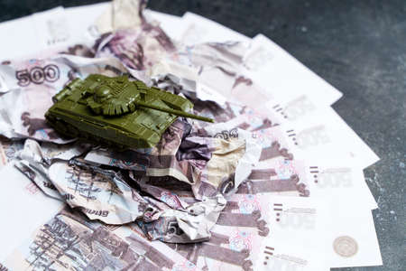 Economic crisis in Russia concept. Toy military tank on Russian rubles. War conflict in Ukraine, economic sanctions and inflation in Russiaの写真素材
