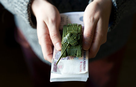 Russian rubles banknotes and toy tank in hands during the war in Ukraine. Inflation, sanctions and the fall of the Russian economy concept. Falling cash savings and budgetの写真素材